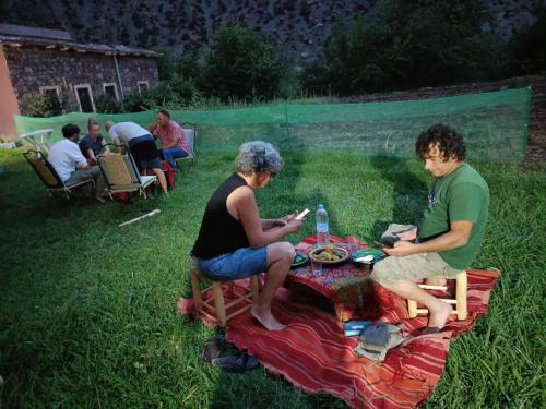 a group of people sitting around a picnic table at Guest House Imdoukal in Aït Tamellil