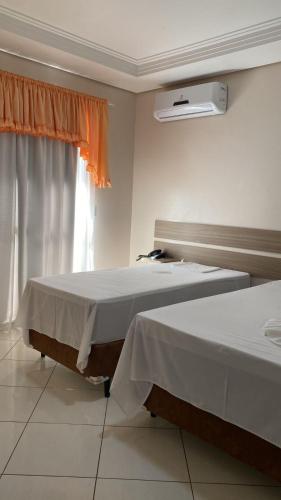 two beds in a room with a window at IMPERADOR Hotel in Lajeado Grande