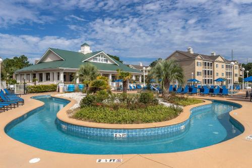 una piscina en un complejo con sillas y edificios azules en Bluegreen Vacations Harbour Lights, en Myrtle Beach