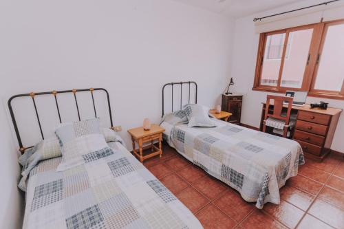 a bedroom with two beds and a desk and window at Casa Marita 11 in Los Llanos de Aridane