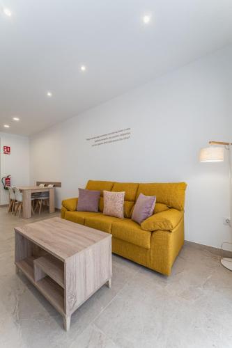 a living room with a yellow couch and a coffee table at CMDreams Platinium- Apartamentos turísticos en el centro de Mérida in Merida