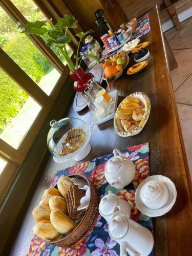 a table topped with plates of pastries and desserts at Pousada Chalés Jardim das Bromélias - Visconde de Mauá in Visconde De Maua