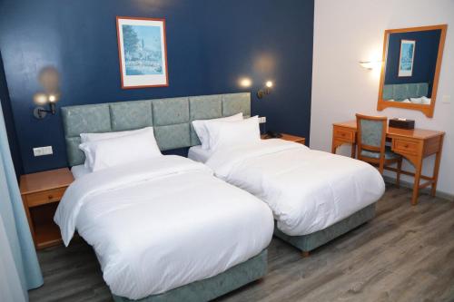 a hotel room with two beds and a desk at El Sheikh Suites Hotel in Beirut