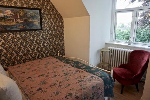 a bedroom with a bed and a chair and a window at Old Roses Guesthouse in Broager