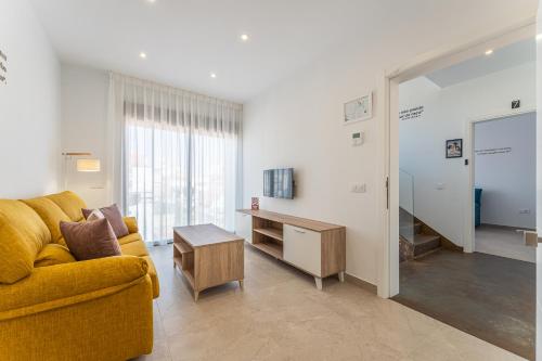 a living room with a yellow couch and a table at CMDreams Platinium- Apartamentos turísticos en el centro de Mérida in Merida