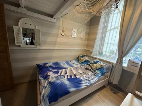 a small bed in a room with a window at Przytulna kawalerka z antresolą w sercu Gdańska in Gdańsk