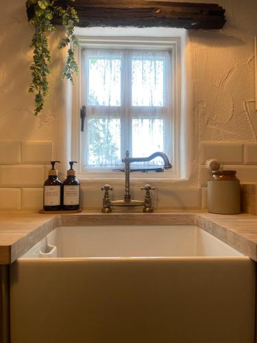 a white sink in a kitchen with a window at The Nest Quaint Luxury Cottage Getaway in Tiragarvan