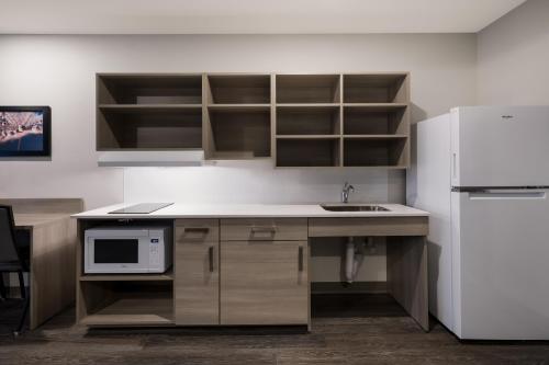 a kitchen with a sink and a white refrigerator at WoodSpring Suites Dearborn Detroit in Dearborn