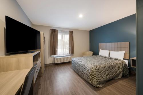a bedroom with a bed and a flat screen tv at WoodSpring Suites Dearborn Detroit in Dearborn
