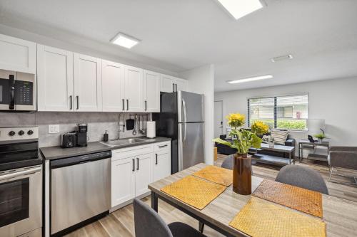 a kitchen with white cabinets and a table with flowers on it at Harbourside Flats in Fort Lauderdale