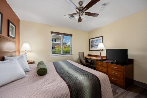 a bedroom with a bed with a television and a desk at Affordable Suites of America Stafford Quantico in Stafford