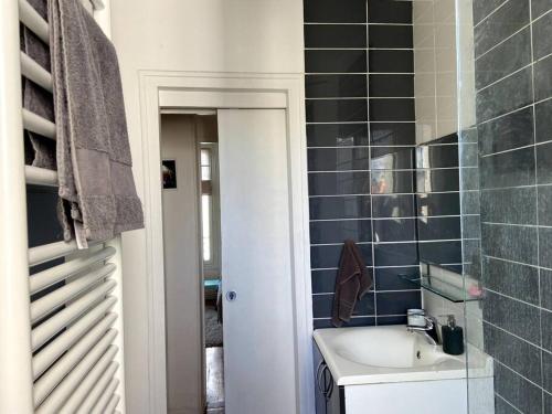 La salle de bains est pourvue d'un lavabo et d'un mur carrelé bleu. dans l'établissement Levallois SO-Ouest Charme & Cosy, à Levallois-Perret