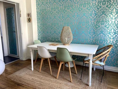 une table de salle à manger avec des chaises et un vase dessus dans l'établissement Levallois SO-Ouest Charme & Cosy, à Levallois-Perret