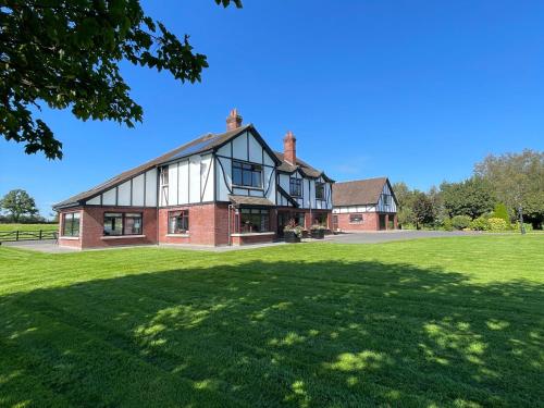 uma casa grande com um relvado verde em frente em Greenfields Country House em Latton