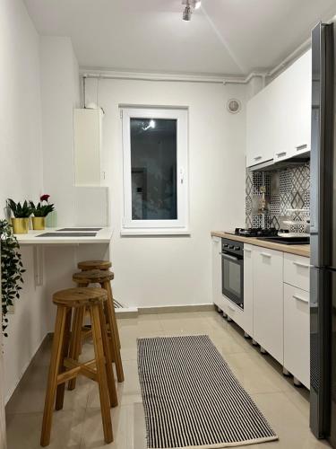 a kitchen with white cabinets and a table and stool at Green Divine Apartament in Popeşti-Leordeni
