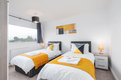 two beds in a bedroom with a window at Spacious Modern Home in Sheffield in Todwick