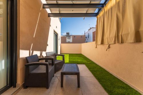 a balcony with chairs and a table and grass at CMDreams Platinium- Apartamentos turísticos en el centro de Mérida in Merida