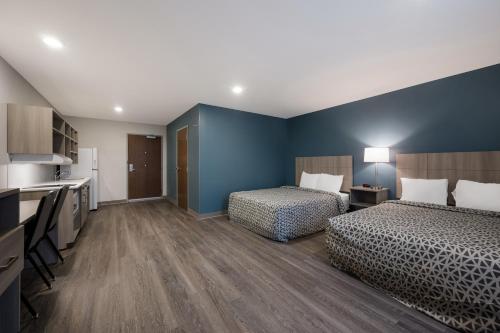 a hotel room with two beds and a kitchen at WoodSpring Suites Dearborn Detroit in Dearborn