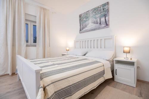 a white bedroom with a large bed and two lamps at Kuća za odmor Kamenjani-Škabrnja in Škabrnje