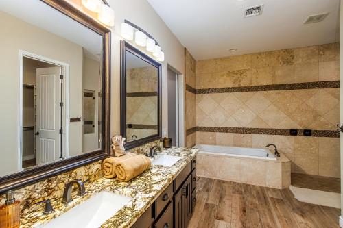 La salle de bains est pourvue de 2 lavabos, d'une baignoire et d'un grand miroir. dans l'établissement Desert Oasis a McCulloch Pool Home, à Lake Havasu City