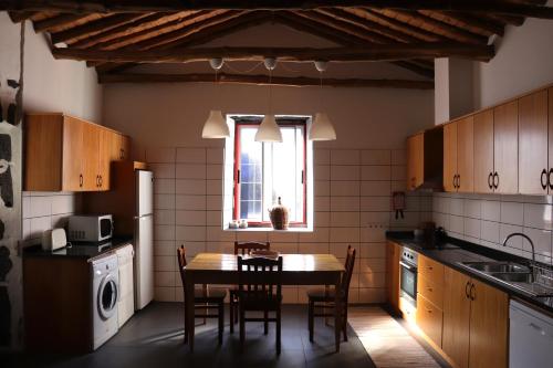 cocina con mesa, sillas y ventana en Adega do Xelica - Holiday Cottage, en Arcos