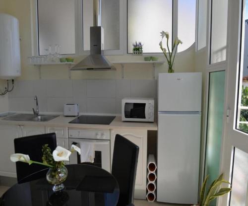 uma cozinha com um frigorífico branco e uma mesa com cadeiras em Navio Azul Apartment no Funchal