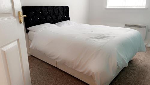 um quarto com uma cama branca e uma cabeceira preta em 2 bedroom apartment, free parking & WIFI near City Centre em Manchester