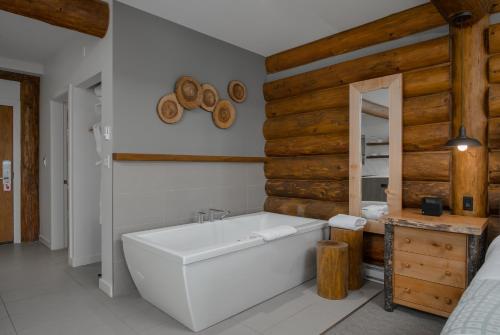 a bathroom with a white tub and wooden walls at Tigh-Na-Mara Seaside Spa Resort in Parksville