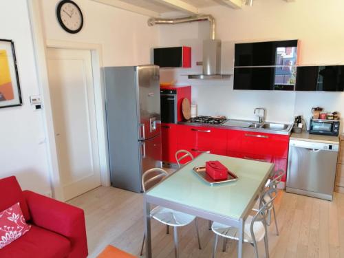 a kitchen with red cabinets and a table and a refrigerator at Appartamento Vivaldi! in Cento