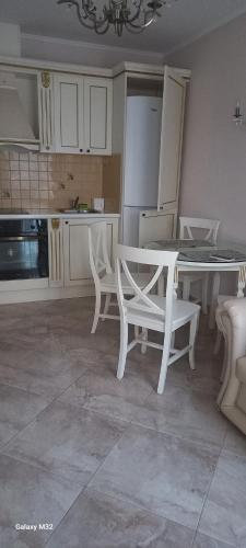 eine Küche mit weißen Stühlen, einem Tisch und einem Tisch sowie einer Küche in der Unterkunft Даун парк Делюкс in Sonnenstrand