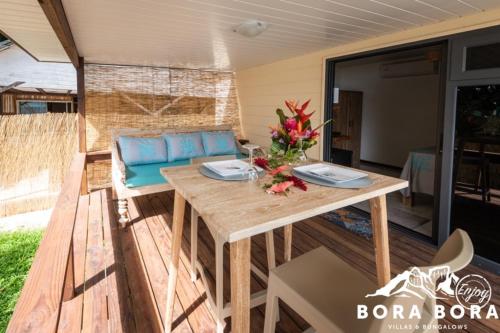 a patio with a wooden table and a couch at Matira Beach Raitea 2 in Bora Bora
