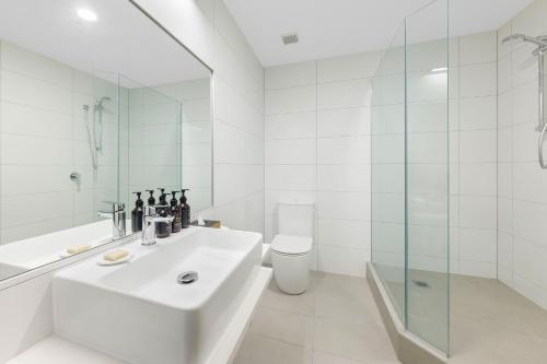 a white bathroom with a sink and a shower at JetPark Hotel Rotorua in Rotorua