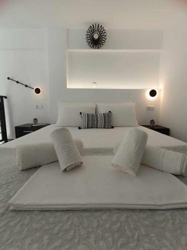 a large white bed with white sheets and pillows at Enigma Boutique Houses Vraxos in Marmarion