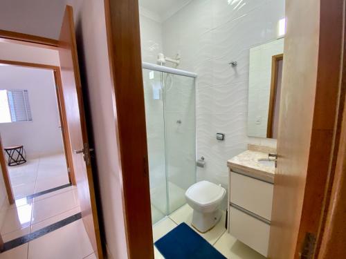 a bathroom with a toilet and a glass shower at Casa no Centro da Cidade/Com ar condicionado in Marília