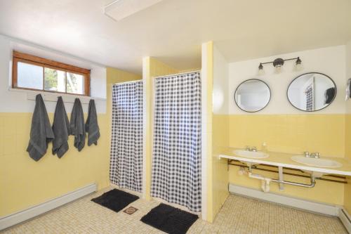 a yellow bathroom with two sinks and two mirrors at HI - Truro Hostel in Truro