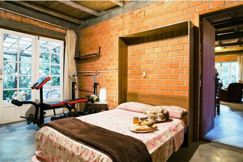 Dormitorio con paredes de ladrillo, cama y silla en Pousada Villa Morena en Florianópolis