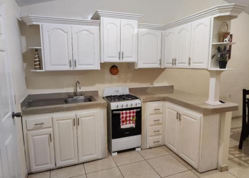 a kitchen with white cabinets and a stove and a sink at Alojamiento en La Ceiba in La Ceiba