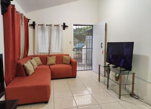 Alojamiento en La Ceiba في لا سيبا: غرفة معيشة مع أريكة حمراء وتلفزيون بشاشة مسطحة