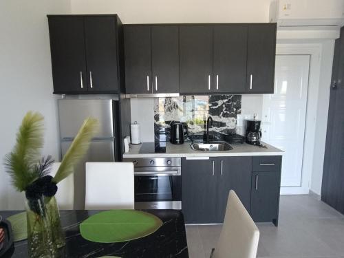 a kitchen with black cabinets and a table with chairs at Enigma Boutique Houses Vraxos in Marmarion