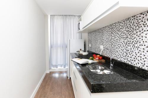 uma cozinha com um lavatório e uma bancada preta em CoVívere em São Paulo