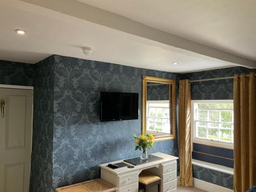 a living room with blue wallpaper and a tv on the wall at The Whitehouse Ross-On-Wye in Ross on Wye