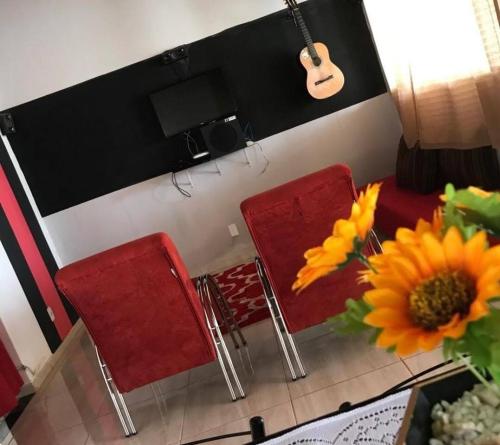 ピレノポリスにあるCasa sousaの赤い椅子とテーブル(ギター付)が備わるお部屋