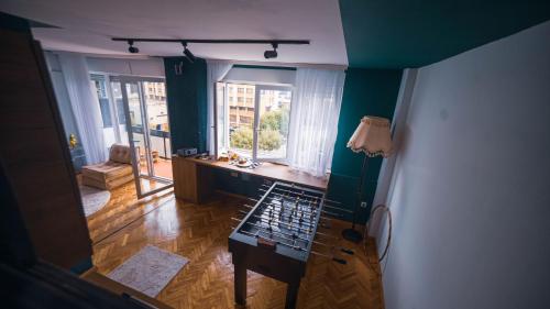um quarto com paredes verdes, uma secretária e janelas em Prishtina In & Out em Pristina