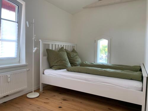 a white bed with green pillows in a white room at Ausspanne Dassow in Dassow
