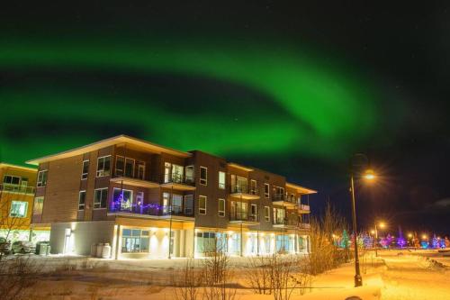 an apartment building with the green northern lights in the sky at Bright Modern Stylish Condo in heart of Downtown (Center) in Whitehorse