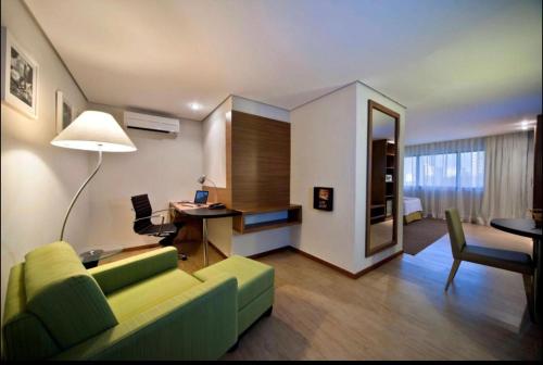 uma sala de estar com um sofá verde e uma secretária em Flat no Hotel Radisson em Belém
