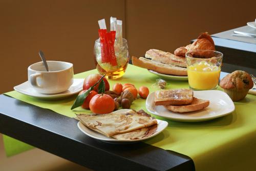 a table with plates of food and a cup of orange juice at Hôtel La Résidence des Artistes in Roscoff
