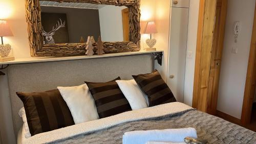 una camera da letto con letto, specchio e cuscini di Chalet Apartment Serenity Lodge a Charmey