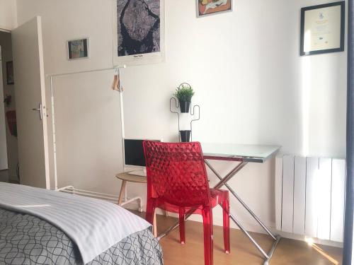 una silla roja sentada en un escritorio en un dormitorio en Le Petit Zénith, en Saint-Herblain