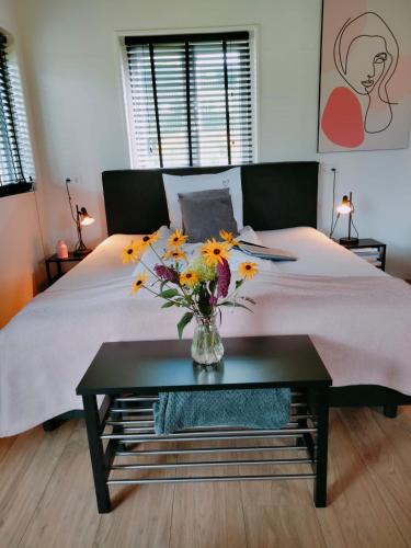 a bedroom with a bed with a vase of flowers on a table at Bed & Breakfast Bij de Wilg in Laren